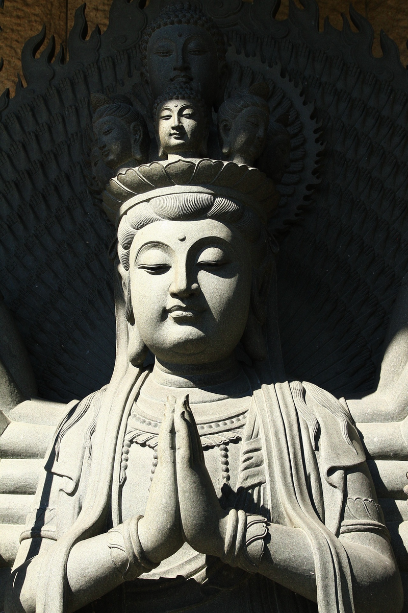 Who are Bodhisattvas and why do they delay their enlightenment to remain on Earth?